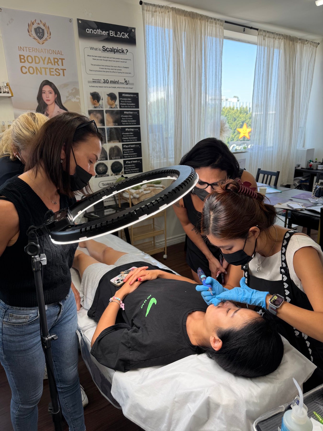 Yu-Jin Lee performing a live lip blush demonstration under a ring light while Master Class students watch