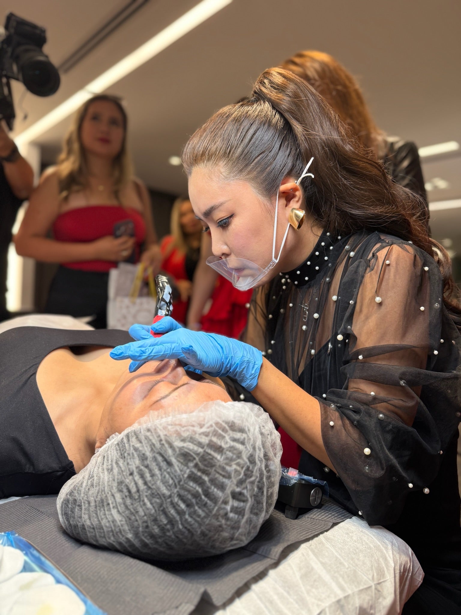 Yu-Jin Lee performing a live lip blush demonstration in front of a seminar audience and camera